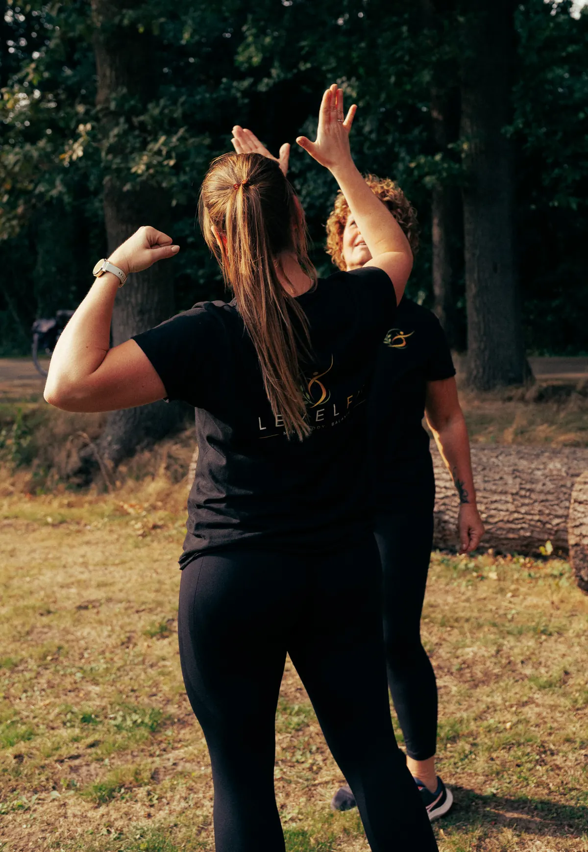 Twee trainers van LevelFit geven elkaar een high five buiten in Twekkelo